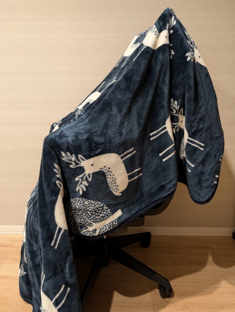 180cmの大判サイズ「CURUN（クルン）」を椅子に掛けている様子。足元までしっかり隠れるので全身の温かさがキープされる